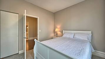 Un dormitorio con una cama, una mesita de noche, una lámpara y una puerta que da a otra habitación.