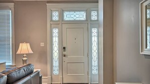 A hallway with a white door, a patterned rug, a leather sofa, and a lamp. - Suites on Seneca - Lovely 2 Bed/1 Bath Apartment (Harrisburg)