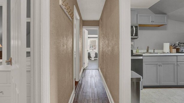 A hallway with a wooden floor leading to a bathroom.