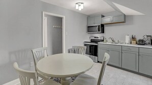 A kitchen with grey cabinets, a white dining table, and a microwave.
