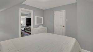 A bedroom with a bed, a dresser, a mirror, and a door.