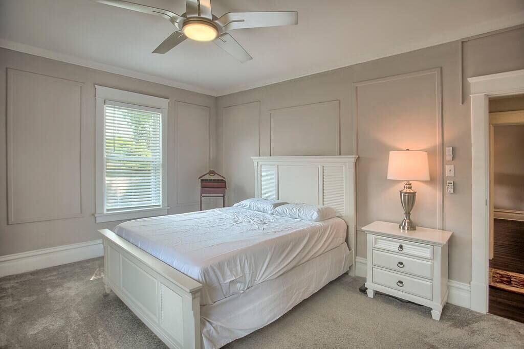A bedroom with a bed, nightstand, lamp, and ceiling fan.