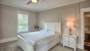 A bedroom with a bed, nightstand, lamp, and ceiling fan.