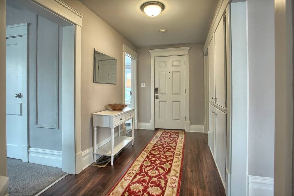 A hallway with a patterned rug, a white console table, and a door.