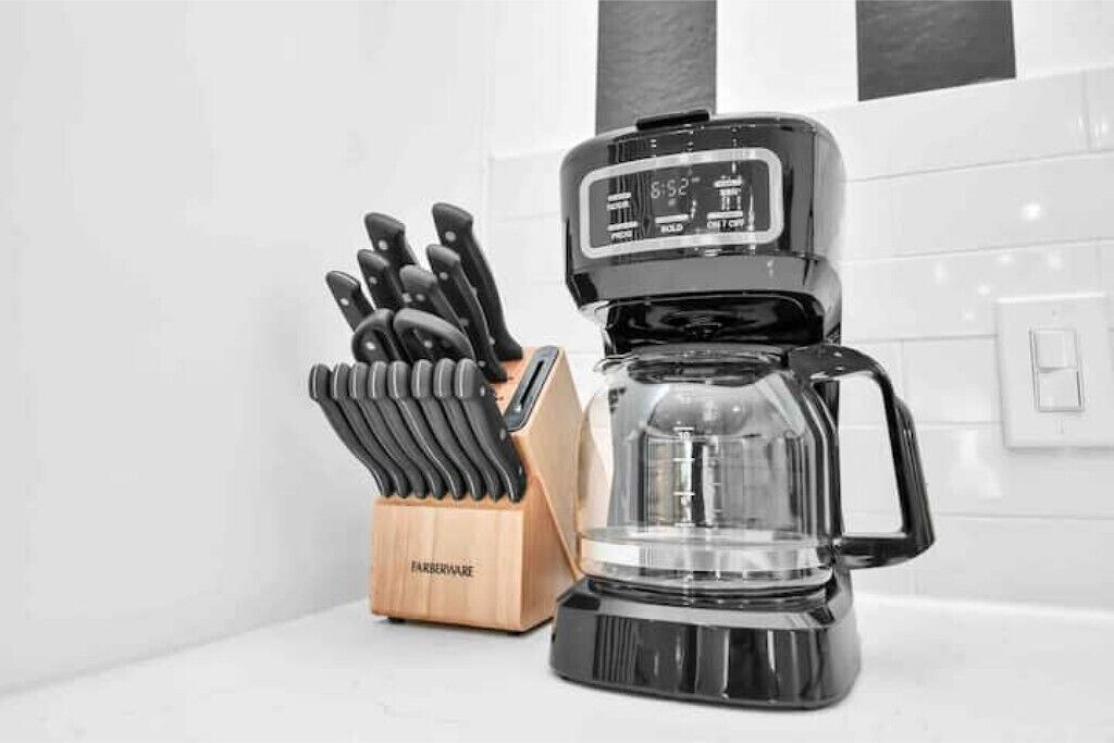 Een koffiezetapparaat met digitaal scherm en een messenblok met messen.