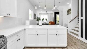 Een moderne keuken met witte kastjes, hanglampen en een centraal eiland.