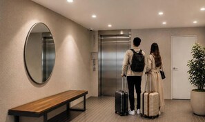 A hotel lobby with a bench, an elevator, and a potted plant.