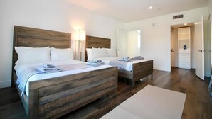 A bedroom with two beds, a wooden headboard, bedside lamps, a dresser, and a walk-in closet.