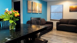 Una sala de estar moderna con una mesa de comedor, dos sofás y un ventanal con persianas.