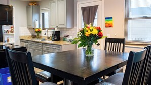 Una cocina moderna con armarios grises, una mesa de comedor con sillas, una cafetera y un florero con flores.