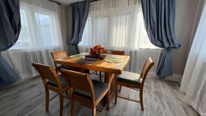 Un comedor con una mesa y sillas de madera, un florero con flores y cortinas translúcidas.