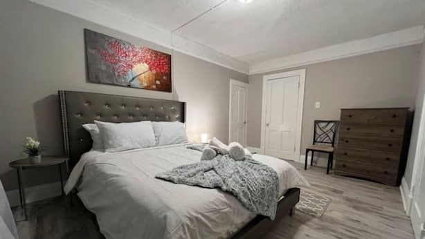 Un dormitorio con una cama grande, una mesita de noche, un aparador y un cuadro en la pared.