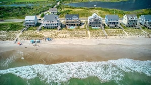 Una propiedad costera con varias casas frente a la playa, una playa de arena y vista al océano.