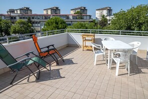 En tagterrasse med udendørs møbler, et bord og stole.