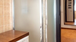 Una cocina con encimera de madera, un electrodoméstico blanco y una puerta de vidrio que da a un pasillo.