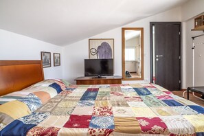 A bedroom with a large bed, a television, a mirror, and a door.