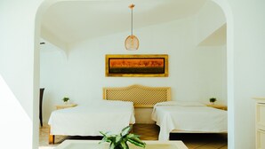 A hotel room with two beds, a painting on the wall, a hanging light fixture, and a small table with a plant. - Bendito Teques (Jojutla)