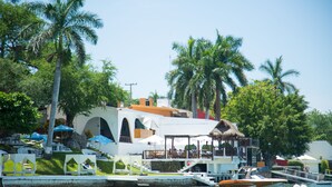 A waterfront property with a pool, lounge chairs, and a restaurant with outdoor seating. - Bendito Teques (Jojutla)