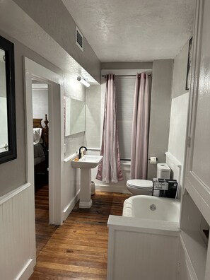A bathroom with a white sink, toilet, and bathtub. There is a mirror above the sink and a window with blinds. - Charming  Water front Florida Home on the beautiful Pithlachascotee River (Port Richey)