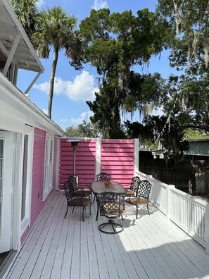 A covered patio with a pink fence, outdoor furniture, and a view of trees and sky. - Charming  Water front Florida Home on the beautiful Pithlachascotee River (Port Richey)