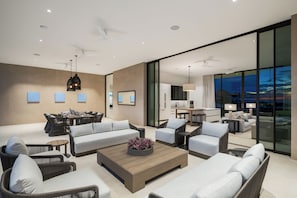 A modern living room with a sofa set, a coffee table, and a dining area with chairs. - Apes Hill Barbados Golf Resort (Orange Hill)