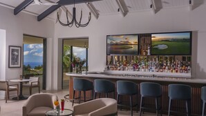 Eine moderne Bar mit einem großen Fernsehbildschirm, Barhocker und Blick auf den Ozean.