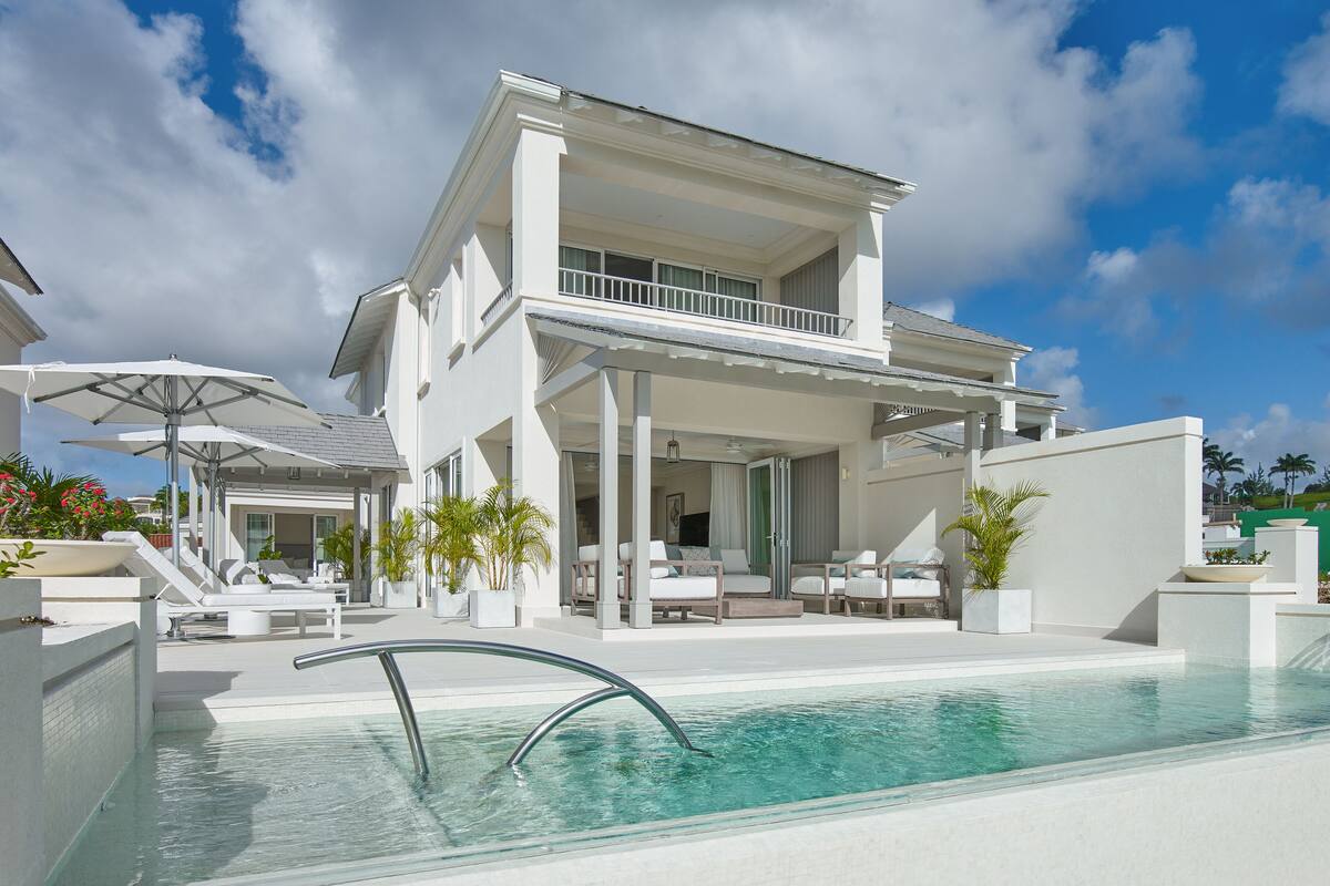 Una casa moderna con piscina, mobiliario exterior y un patio cubierto.