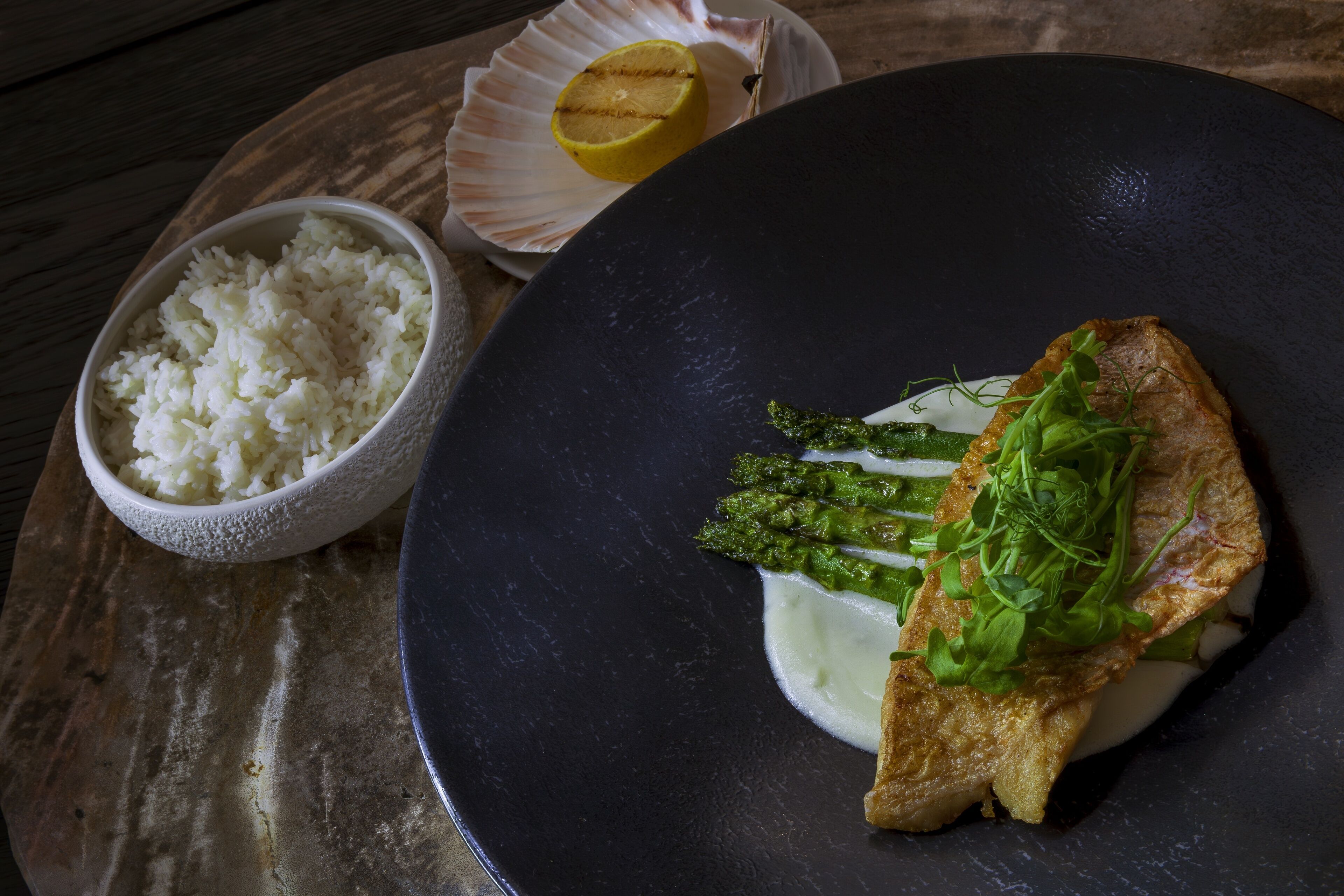 A plate of food with rice, asparagus, and a piece of fish.