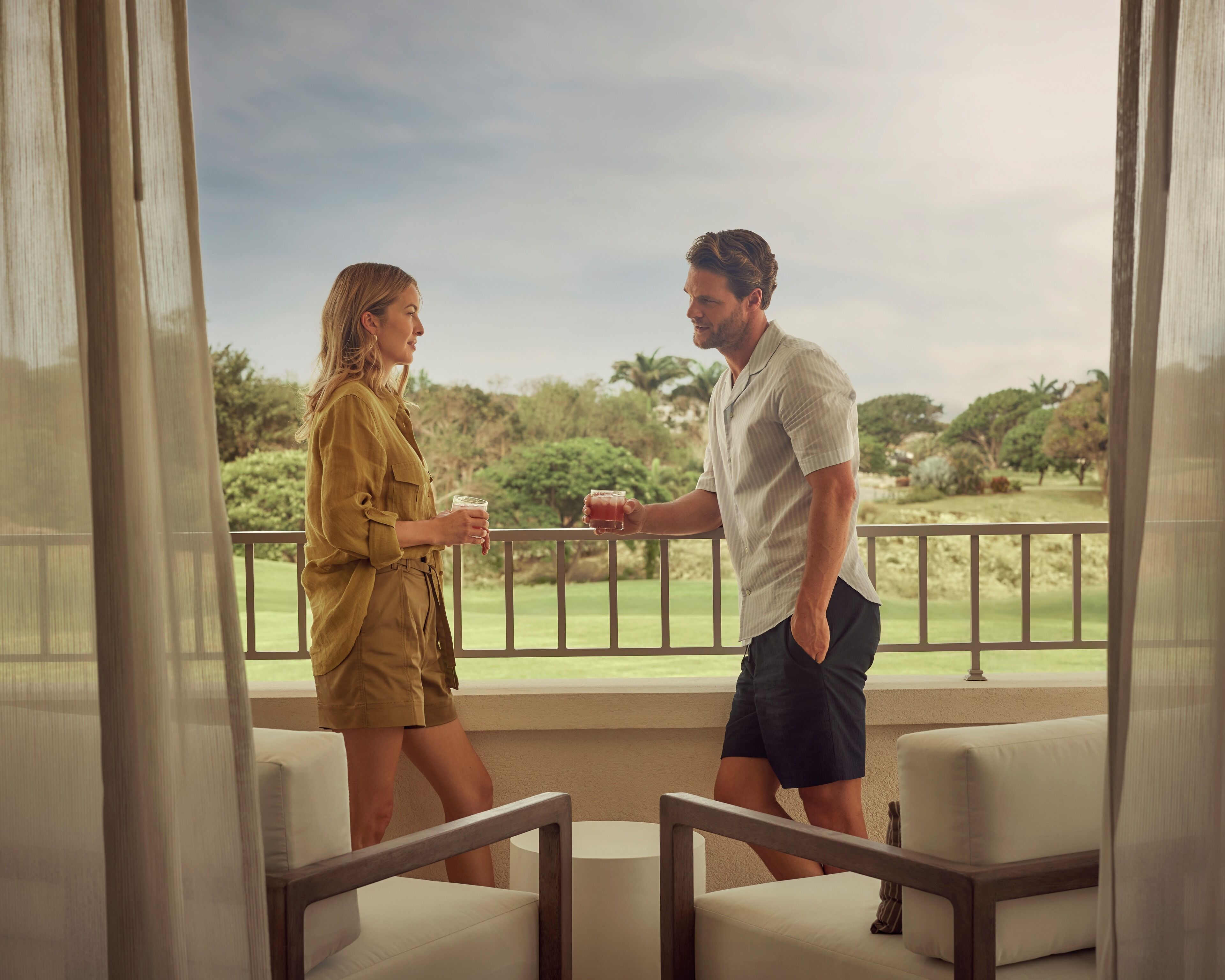 Una pareja de pie en un balcón con vistas a un campo de golf.