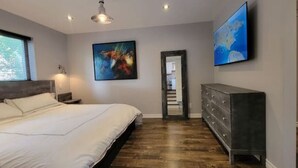 A bedroom with a large bed, a dresser, and two paintings on the wall. - Family Friendly Century Home - 3 Bedrooms, 2 Baths (Toronto)
