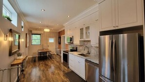A modern kitchen with stainless steel appliances, white cabinetry, and a wooden floor. - Family Friendly Century Home - 3 Bedrooms, 2 Baths (Toronto)