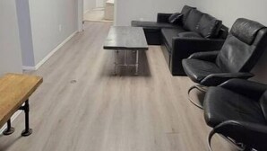 A modern waiting area with a wooden coffee table, black leather chairs, and a flat-screen TV mounted on the wall. - Family Friendly Century Home - 3 Bedrooms, 2 Baths (Toronto)