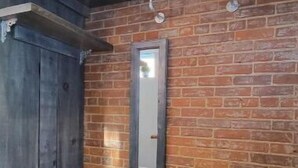 A room with a brick wall, a wooden bench, and a mirror. - Family Friendly Century Home - 3 Bedrooms, 2 Baths (Toronto)
