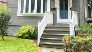 A two-story house with a front porch, a front door, and a small window above the door. - Serenity in South Wedge: desirable walking community meets vibrant tranquillity! (Rochester)