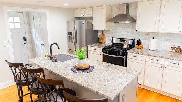 A modern kitchen with a central island, stainless steel appliances, and wooden chairs. - Serenity in South Wedge: desirable walking community meets vibrant tranquillity! (Rochester)