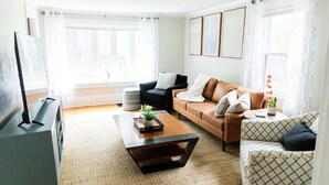 A living room with a sofa, a coffee table, and a television. - Serenity in South Wedge: desirable walking community meets vibrant tranquillity! (Rochester)
