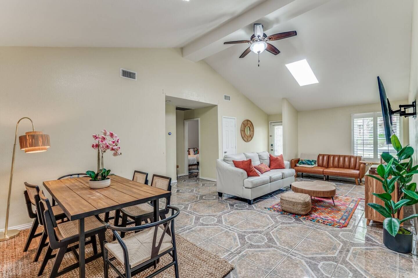 A spacious living area with a dining table, chairs, a white sofa, and a brown leather couch.