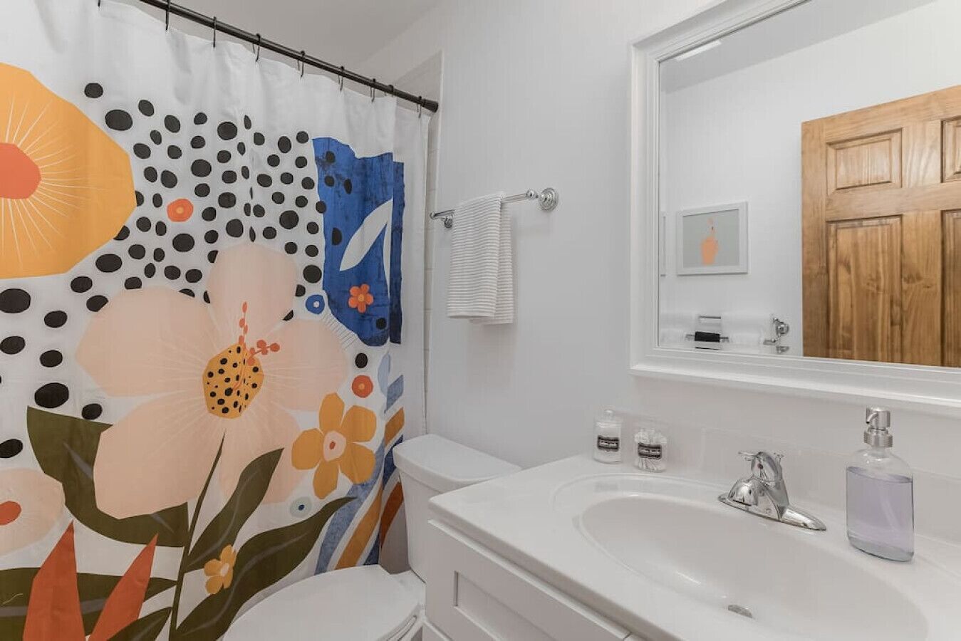 A bathroom with a white sink, a mirror, and a shower curtain with a floral pattern.