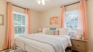 A bedroom with a bed, nightstands, a ceiling fan, and a window with blinds.