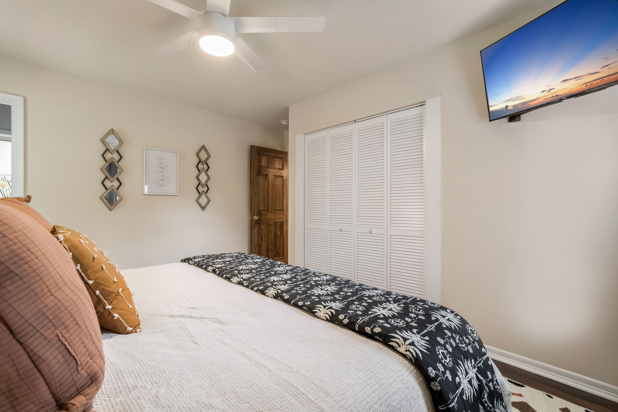 Une chambre à coucher avec un lit, un ventilateur de plafond, une télévision et un placard.