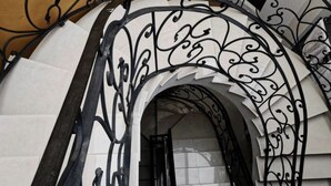 Uma escadaria de ferro forjado ornamentada com parede revestida de azulejos brancos.