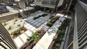 A courtyard with a central garden, steps leading to a balcony, and a parking area with cars. - UT North Campus Apt Unit 12 /1 Mile to Moody Center
 (Austin)