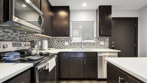 A modern kitchen with dark cabinets, a stainless steel range, and a tiled backsplash. - UT North Campus Apt Unit 12 /1 Mile to Moody Center
 (Austin)