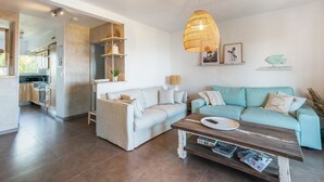 Un salon moderne avec un canapé, une table basse et un luminaire suspendu.