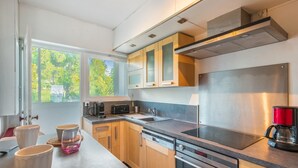 Une cuisine moderne dotée de meubles en bois, d’appareils électroménagers en acier inoxydable et d’une grande fenêtre qui laisse entrer la lumière naturelle.