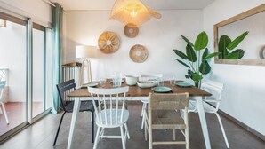 Un coin repas avec une table en bois, des chaises blanches et un luminaire suspendu.