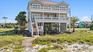 Una casa sulla spiaggia su due piani, con un balcone, un pontile di legno e un cartello con la scritta 'No Swimming'.