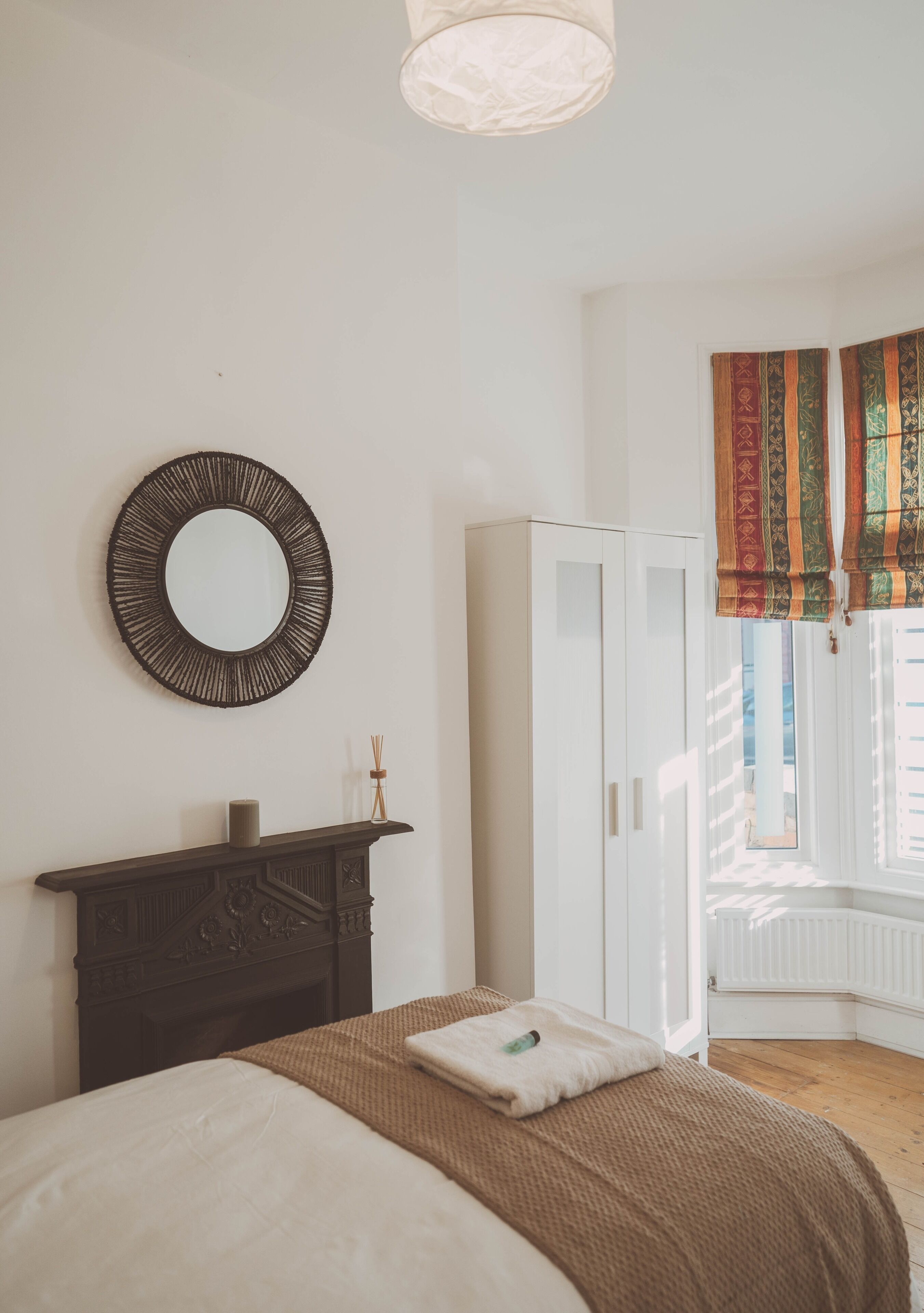 A bedroom with a bed, a dresser, a mirror, and a window with curtains.