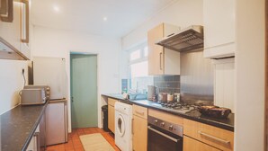 Eine kompakte Küche mit Waschmaschine, Backofen und kleinem Kühlschrank.