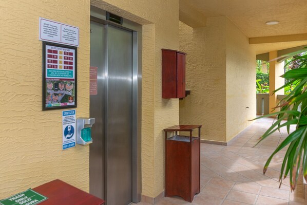 A hallway with a trash bin, a sanitizer dispenser, and a map of the property.